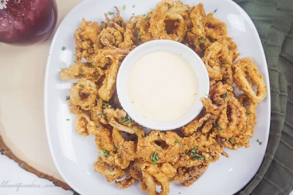 Gluten-Free Fried Calamari with Sriracha Lemon Basil Aioli -- These restaurant quality gluten-free fried calamari with sriracha lemon basil dipping sauce are sure to knock the socks off of all of your guests! They are perfectly seasoned, very crunchy yet tender. -- lilsweetspiceadvice.com #glutenfreefriedcalamari #friedcalamari #glutenfreeappetizers