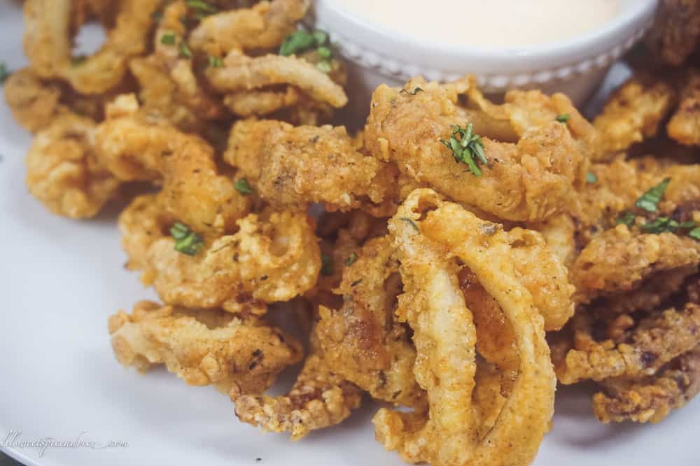 Gluten-Free Fried Calamari with Sriracha Lemon Basil Aioli -- These restaurant quality gluten-free fried calamari with sriracha lemon basil dipping sauce are sure to knock the socks off of all of your guests! They are perfectly seasoned, very crunchy yet tender. -- lilsweetspiceadvice.com #glutenfreefriedcalamari #friedcalamari #glutenfreeappetizers