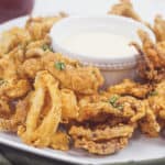 Gluten-Free Fried Calamari with Sriracha Lemon Basil Aioli -- These restaurant quality gluten-free fried calamari with sriracha lemon basil dipping sauce are sure to knock the socks off of all of your guests! They are perfectly seasoned, very crunchy yet tender. -- lilsweetspiceadvice.com #glutenfreefriedcalamari #friedcalamari #glutenfreeappetizers